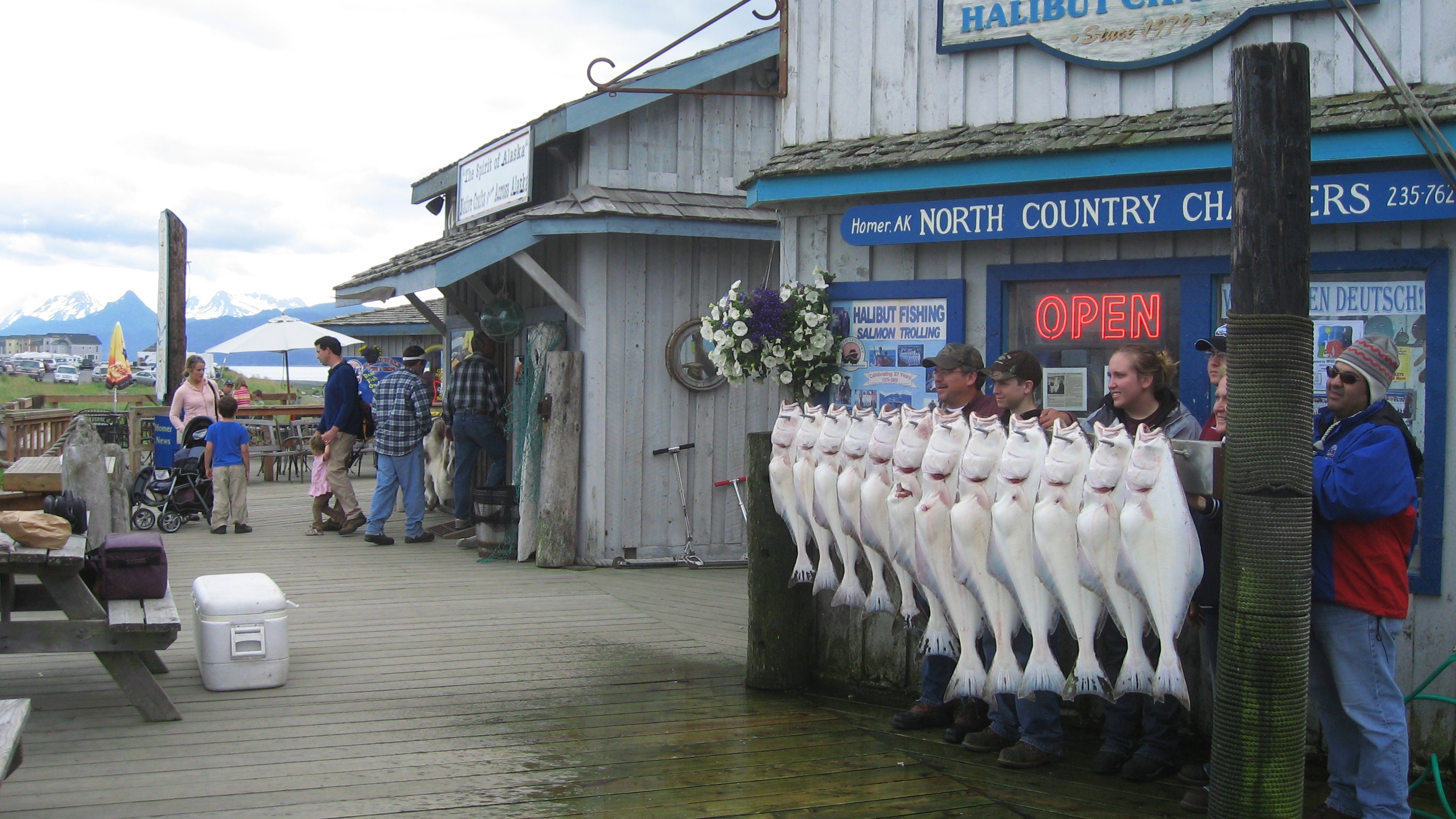 Historical 2008 photograph of anglers and halibut outside the signed North Country Charters storefront on Homer Spit